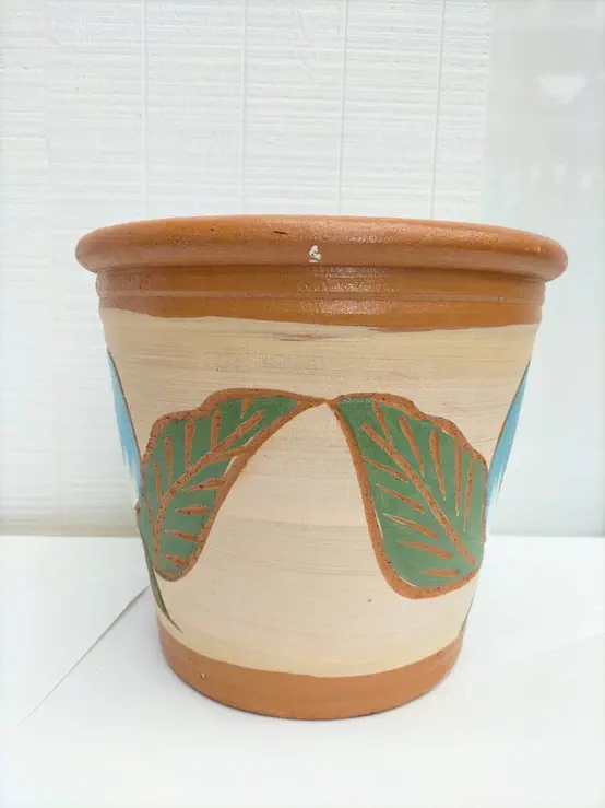 bb100287 Håndlavet thailandsk lerpotte med tyk kant. Med lyseblå og hvid blomsterknop samt blade på flødefarvet baggrund bb100287 Håndlavet thailandsk lerpotte med tyk kant. Med lyseblå og hvid blomsterknop samt blade på flødefarvet baggrund